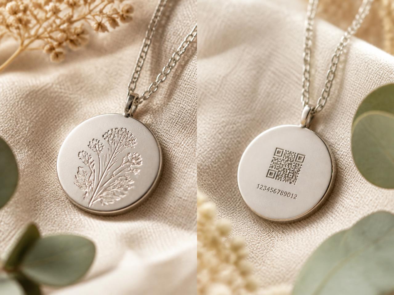 A silver pendant shown front and back, with a small QR code and engraved digits on the reverse